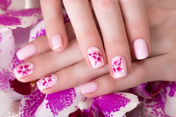 Tiro bela manicura com flores em dedos femininos. Desenho de unhas. Close-up — Fotografia de Stock