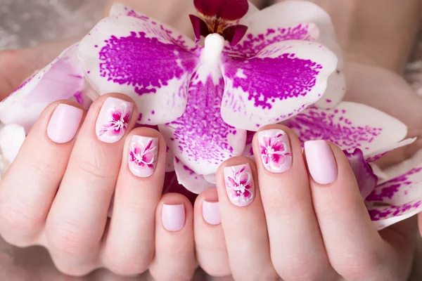 Tiro bela manicura com flores em dedos femininos. Desenho de unhas. Close-up — Fotografia de Stock