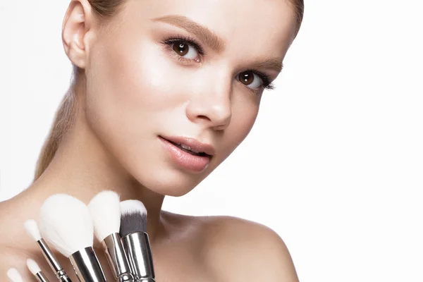 Beautiful young girl with a light natural make-up, brushes for cosmetics. Beauty face. — Stock Photo, Image