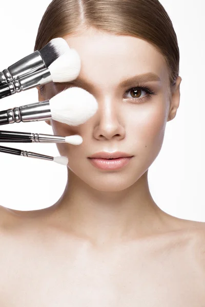 Hermosa joven con un maquillaje natural ligero, cepillos para cosméticos. Cara de belleza . — Foto de Stock