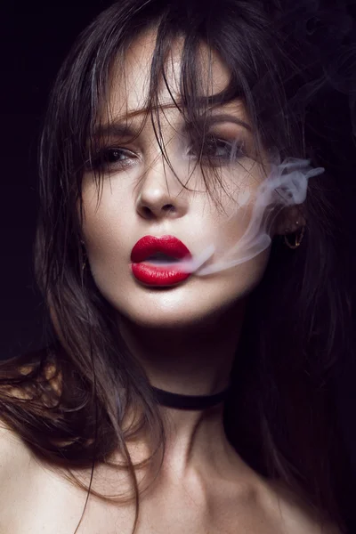 Hermosa chica morena sexy con maquillaje brillante, labios rojos, humo de la boca. cara de belleza . — Foto de Stock