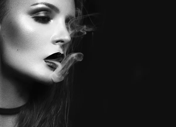 Hermosa chica morena sexy con maquillaje brillante, labios rojos, humo de la boca. Cara de belleza. Blanco y negro — Foto de Stock