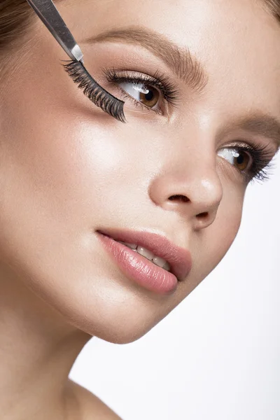 Beautiful young girl with a light natural make-up, Eyebrow Tweezers and False eyelashes. Beauty face. — Stock Photo, Image