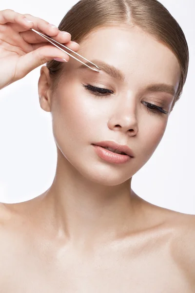 Beautiful young girl with a light natural make-up, Eyebrow Tweezers and French manicure. Beauty face. — Stock Photo, Image