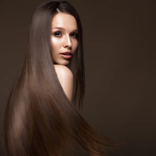 Beautiful brunette girl in move with a perfectly smooth hair, and classic make-up. Beauty face. — Stock Photo, Image