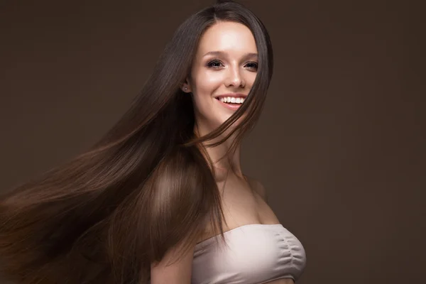 Schöne brünette Mädchen in Bewegung mit einem perfekt glatten Haar und klassischem Make-up. Schönheit Gesicht. — Stockfoto