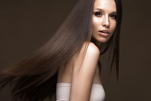 Menina morena bonita em movimento com um cabelo perfeitamente liso e maquiagem clássica. Cara de beleza . — Fotografia de Stock