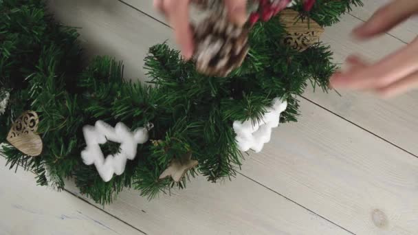 Las manos de las mujeres decoran una corona de árbol de Navidad con conos y ramas de serbal. Feliz Navidad y un feliz año nuevo — Vídeo de stock