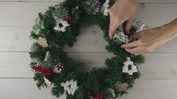 Las manos de las mujeres decoran una corona de árbol de Navidad con conos y ramas de serbal. Feliz Navidad y un feliz año nuevo — Vídeo de stock