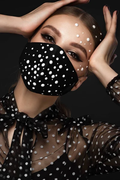 Egy gyönyörű nő portréja fekete maszkban gyöngyökkel és klasszikus sminkkel. Maszk üzemmód a kovid világjárvány idején — Stock Fotó