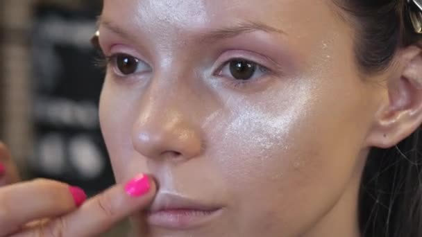 Макияж художник применяет косметику к лицу молодой женщины в салоне красоты — стоковое видео