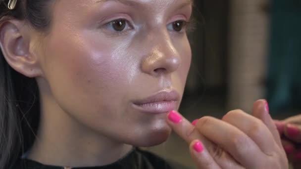 Sminkes alkalmazni kozmetikumok arcát a fiatal nő szépségszalonban — Stock videók
