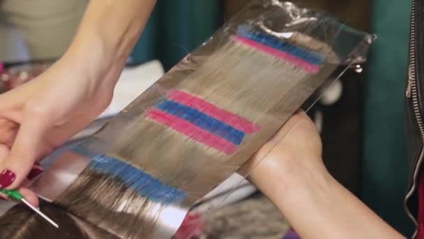 Перукар фарбує клієнтів світле волосся синьо-червоного кольору . — стокове відео
