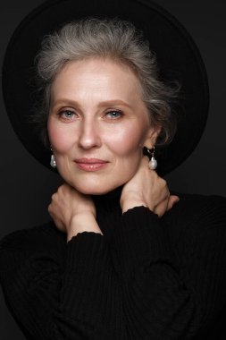 Siyah gömlekli, güzel, yaşlı bir kadının portresi. Klasik makyaj ve gri saçlı..