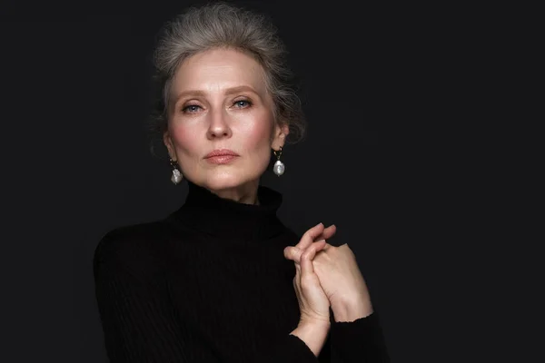 Retrato de uma bela mulher idosa em uma camisa preta com maquiagem clássica e cabelos grisalhos. — Fotografia de Stock
