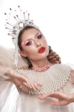 Parlak makyajlı, beyaz elbiseli ve aksesuarlı yaratıcı bir kadın.