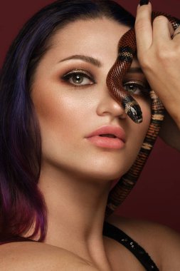 Güzel esmer kız modeli, elinde yılanla akşam makyajı yapıyor. Güzel surat..