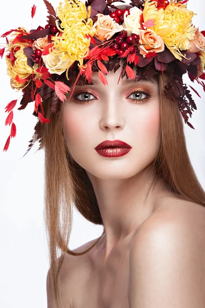 Gyönyörű vörös hajú lány fényes őszi koszorú, a levelek és virágok. szépség arc. — Stock Fotó