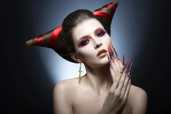 The girl in an image of the demon-tempter with long nails and haircut in the form of horns. — Stock Photo, Image