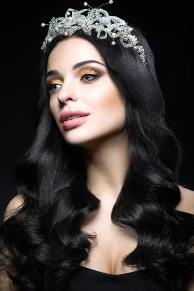Mulher de cabelos escuros bonita com uma coroa de pedras preciosas, cachos e maquiagem à noite. Cara de beleza . — Fotografia de Stock