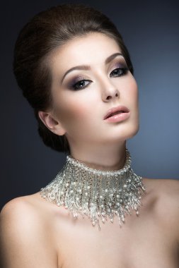 Akşam makyaj ve saç modeli ve boynundaki büyük bir kolye ile güzel bir kadın. Güzellik.