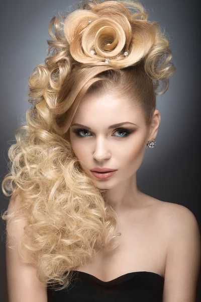 Schöne blonde Mädchen im Abendkleid mit einer ungewöhnlichen Frisur in Form von Rosen und hellem Make-up. Schönheit Gesicht. — Stockfoto
