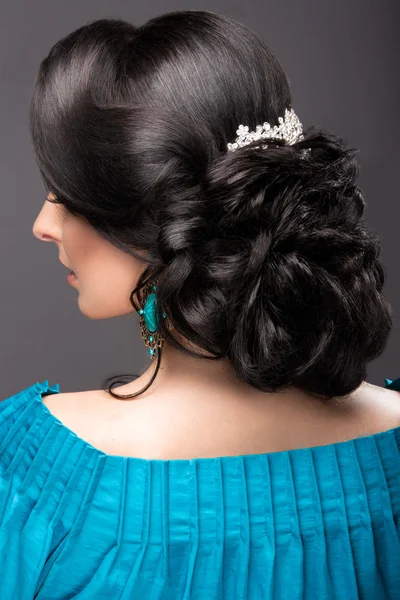 Menina bonita em um vestido azul com maquiagem à noite e penteado. Cara de beleza. Penteado visão traseira — Fotografia de Stock