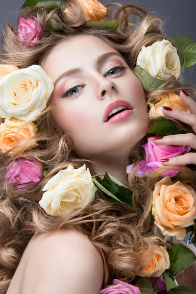 Retrato de una hermosa chica con un maquillaje rosa suave y un montón de flores en el pelo. Cara de belleza . — Foto de Stock