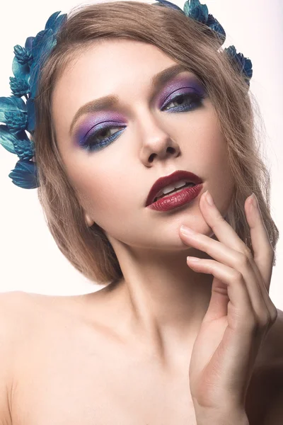 Schöne blonde Mädchen mit hellem Make-up und lila blauen Blumen im Haar. Schönheit Gesicht. — Stockfoto