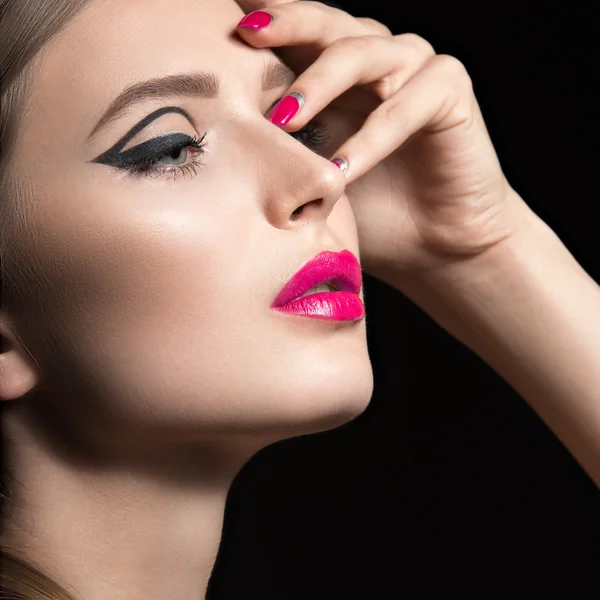 Beautiful girl with unusual black arrows on eyes and pink lips and nails. Beauty face. Picture taken in the studio on a black background. — Stock Photo, Image