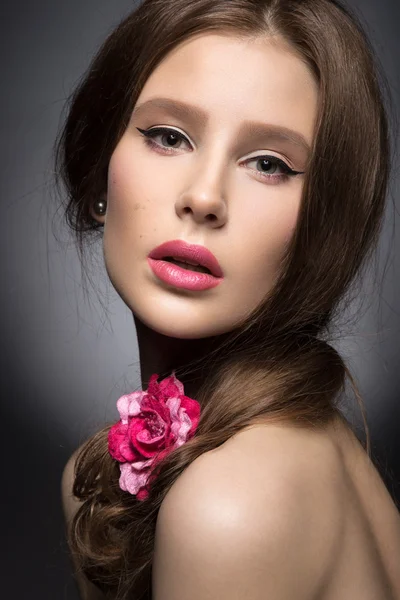 Schönes Mädchen mit rosa Lippen und einer Rose im Haar. Schönheit Gesicht. — Stockfoto