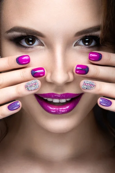 Hermosa chica con un maquillaje de noche brillante y manicura púrpura con pedrería. Diseño de uñas. Cara de belleza . — Foto de Stock