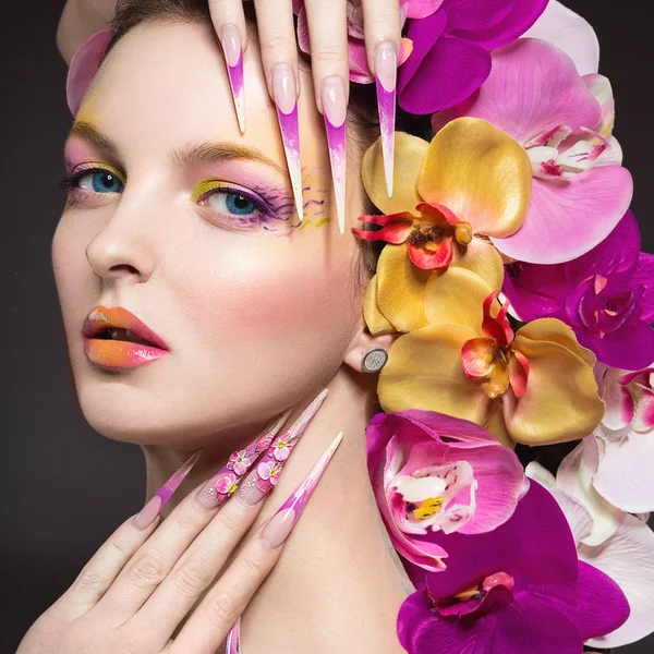 Mooie vrouw met lange nagels, perfecte huid, haren van orchideeën. — Stockfoto