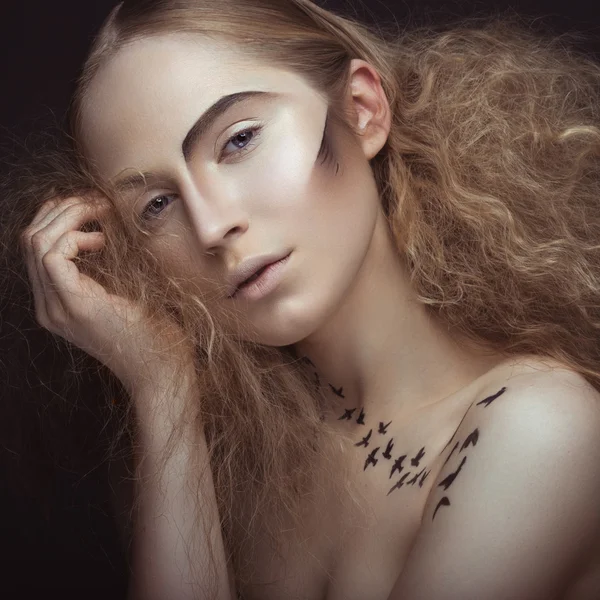 Hermosa chica con un patrón en el cuerpo en forma de pájaros, maquillaje creativo y peinado exuberante. Cara de belleza . —  Fotos de Stock