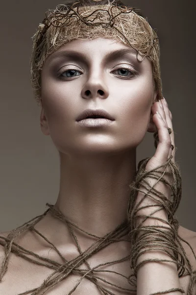 Beautiful girl with a bronze skin, pale makeup and unusual accessories. Art beauty image. Beauty face.