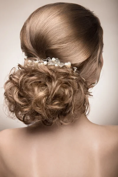 Retrato de uma mulher bonita em um vestido de noiva à imagem da noiva. penteado as costas — Fotografia de Stock