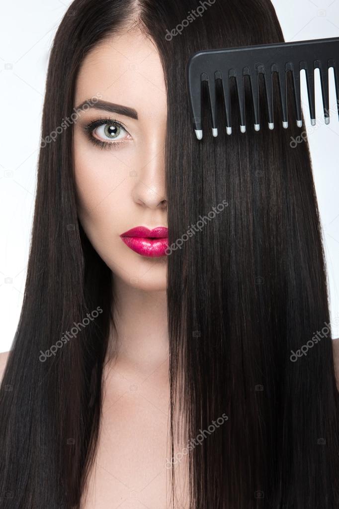 Beautiful brunette girl with a perfectly smooth hair, hairbrush and classic make-up. Beauty face. 