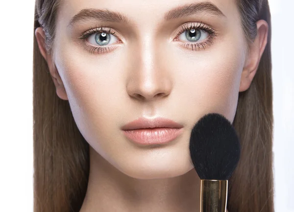 Mooi meisje met een lichte natuurlijke make-up en schoonheid tools in de hand. — Stockfoto