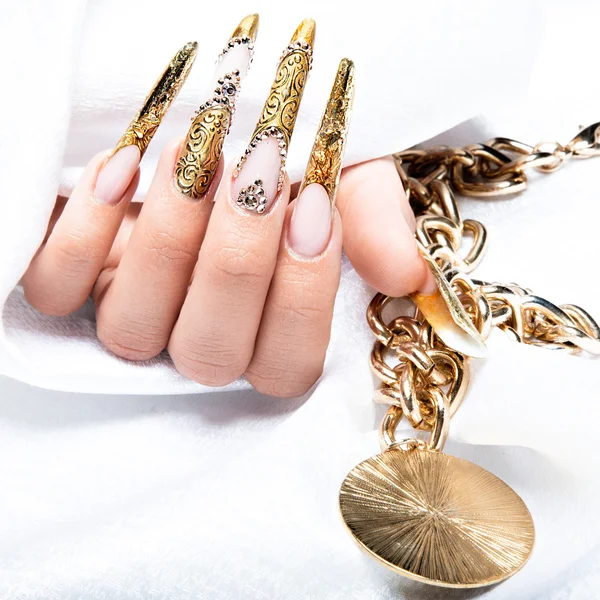 Beautiful long nails in a gold design with rhinestones. Nail art.