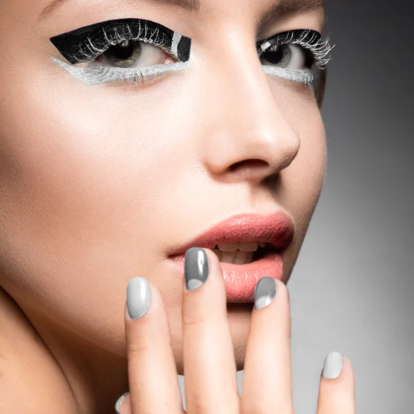 Beautiful girl with bright creative fashion makeup and Grey nail polish. Art beauty design.