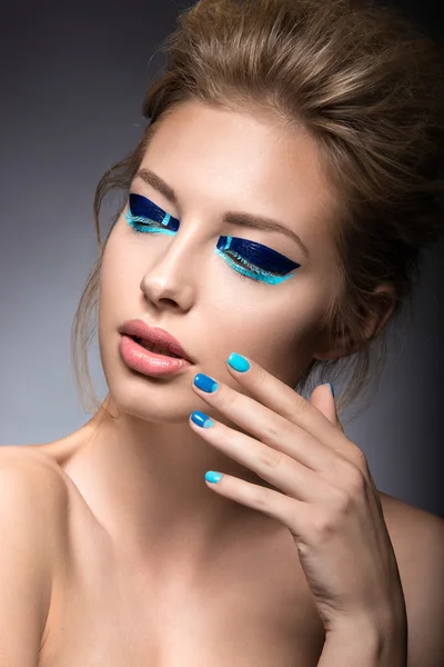 Beautiful girl with bright creative fashion makeup and blue nail polish. Art beauty design.
