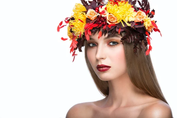 Menina bonita com grinalda de outono brilhante de folhas e flores. Cara de beleza. Foto tirada no estúdio sobre um fundo branco . — Fotografia de Stock