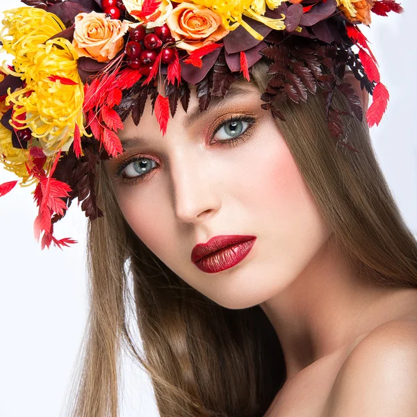 Schönes Mädchen mit hellem Herbstkranz aus Blättern und Blumen. Schönheit Gesicht. Foto aus dem Studio auf weißem Hintergrund. — Stockfoto