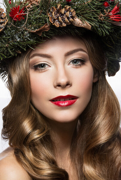 Beautiful girl with a wreath of Christmas tree branches and cones. New Year image. Beauty face.