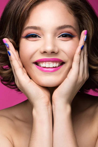 Hermosa chica modelo con maquillaje rosa brillante, sonrisa y esmalte de uñas de colores. Cara de belleza. Clavos cortos de colores — Foto de Stock