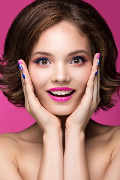 Hermosa chica modelo con maquillaje rosa brillante, sonrisa y esmalte de uñas de colores. Cara de belleza. Clavos cortos de colores — Foto de Stock