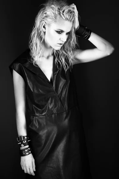 Daring girl model in black leather dress, style of rock, dark make-up, wet hair and bracelets on her arms. — Stock Photo, Image