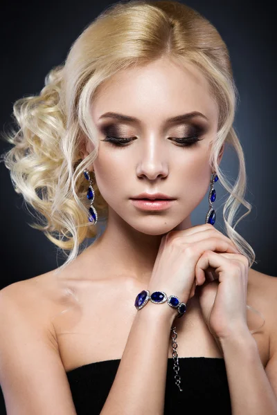 Vacker blond flicka i en svart klänning med frisyr form av vågor och ljusa makeup på kvällen. Skönhet ansikte. — Stockfoto