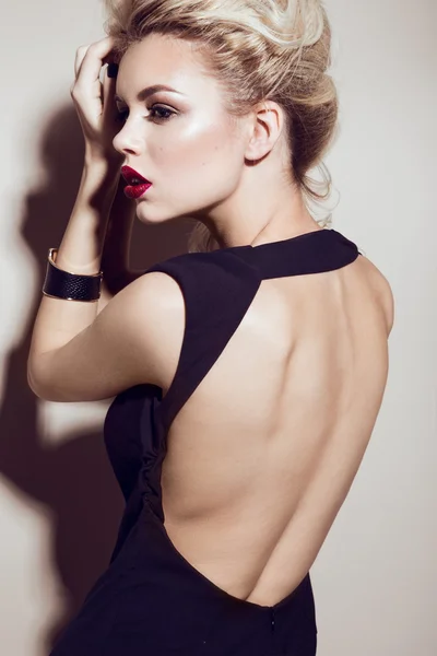 Bella ragazza bionda sexy con labbra sensuali, capelli alla moda, abito nero e accessori in oro. Bellezza viso . — Foto Stock