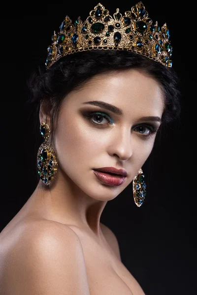 Beautiful brunette girl with a golden crown, earrings and professional evening make-up. Beauty face. — Stock Photo, Image